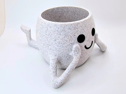 Vaso decorativo grigio con volto sorridente e gambe su sfondo chiaro