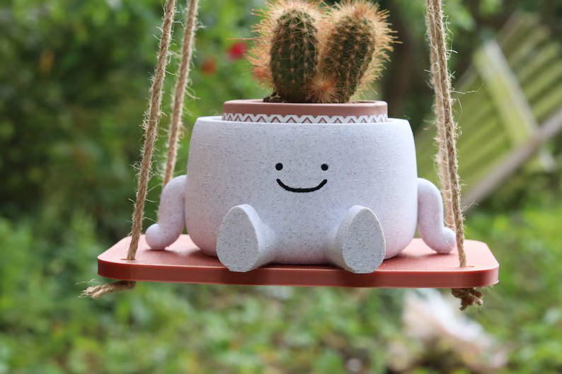 Vaso sospeso sorridente con cactus su base in legno