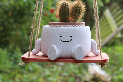 Vaso sospeso sorridente con cactus su base in legno