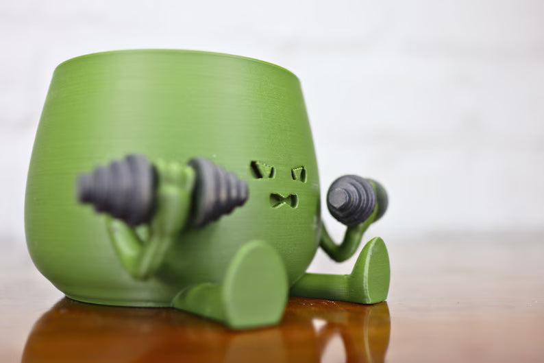 Vaso verde decorativo a forma di personaggio che solleva pesi con cactus sullo sfondo