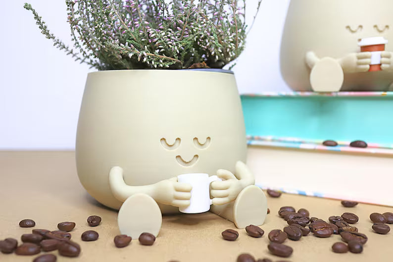 Vaso color crema con personaggio che tiene una tazza circondato da chicchi di caffè
