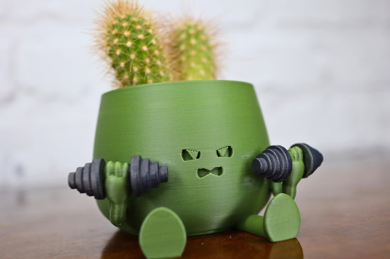 Vaso moderno verde con personaggio ironico e cactus inserito nella parte superiore